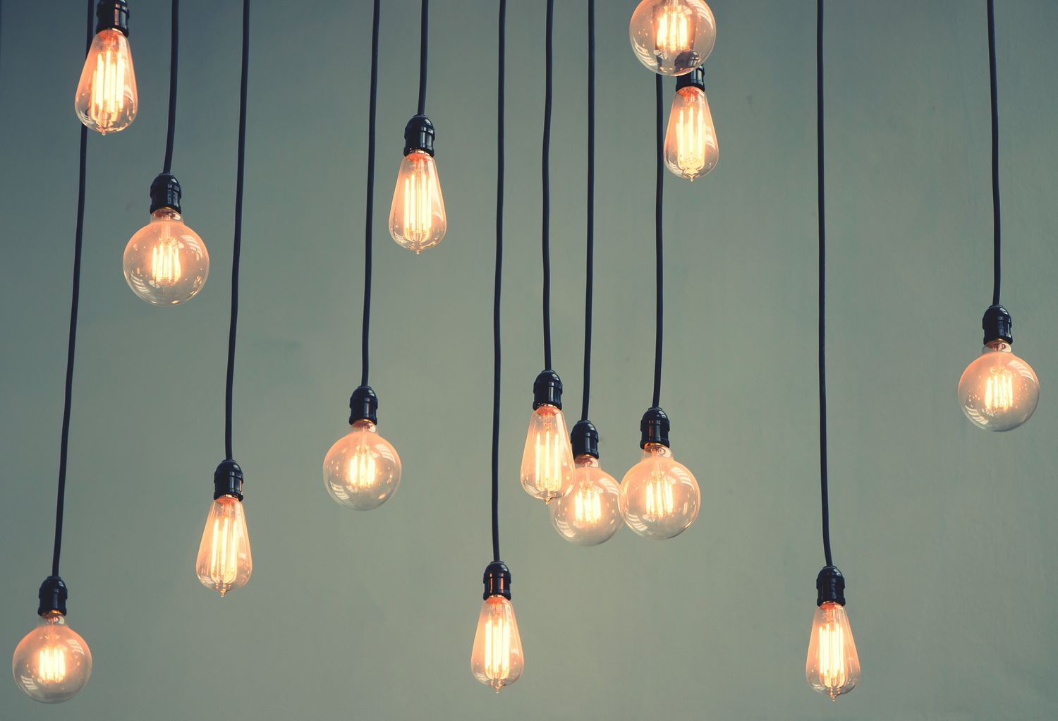 Low Angle View Of Illuminated Light Bulbs Hanging Against Wall