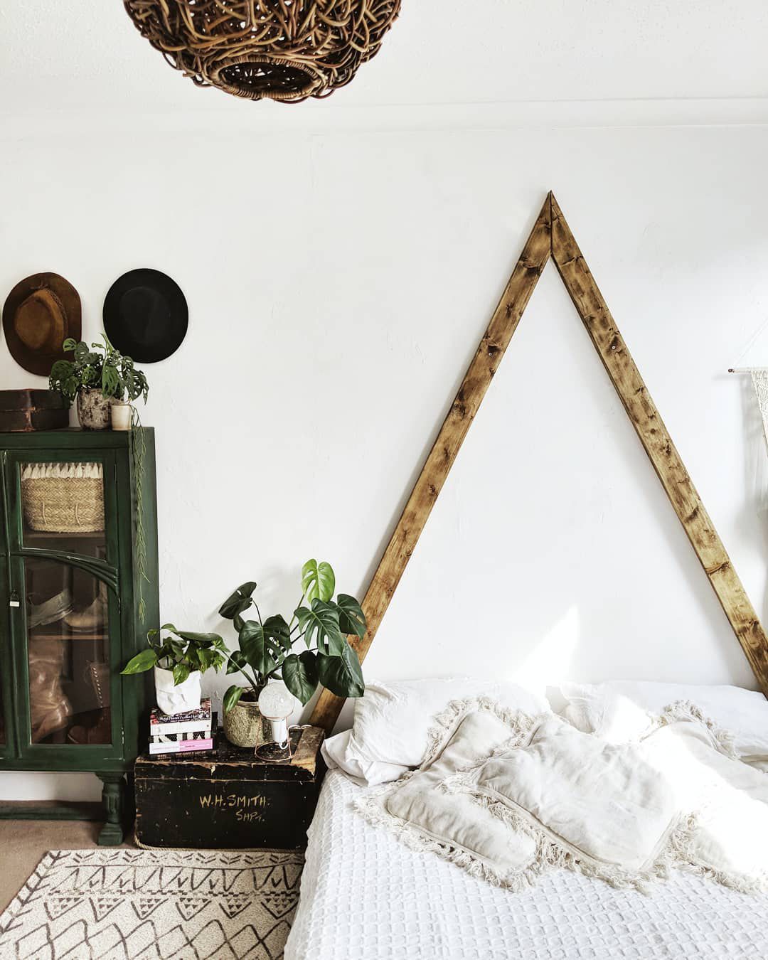 Dormitorio con un triángulo de madera detrás de la cama