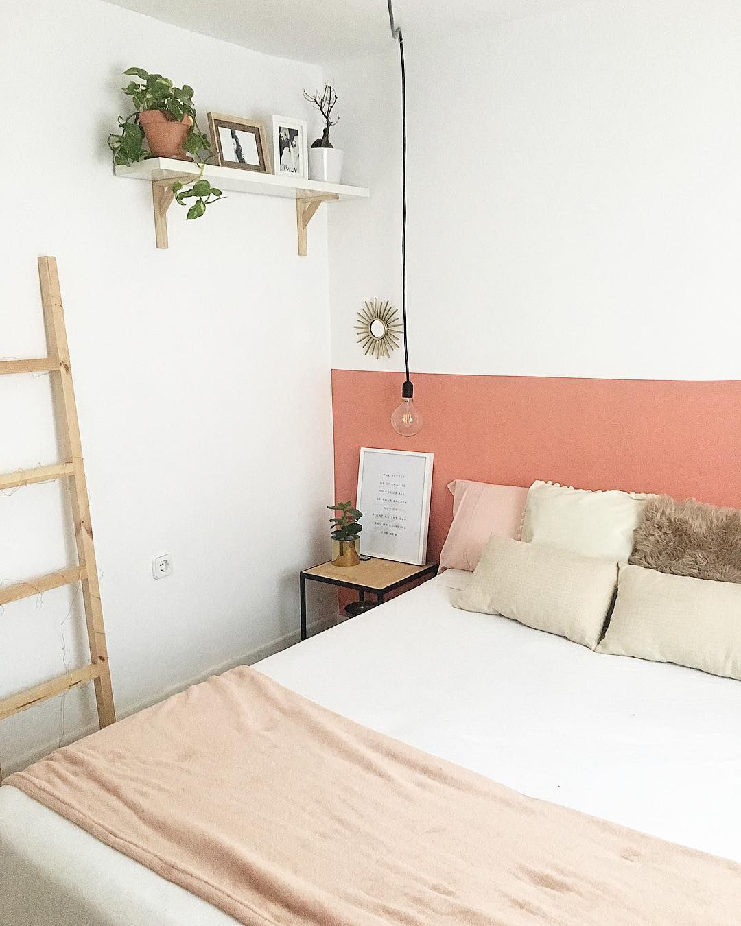 Um quarto com uma parede branca e pêssego atrás da cama