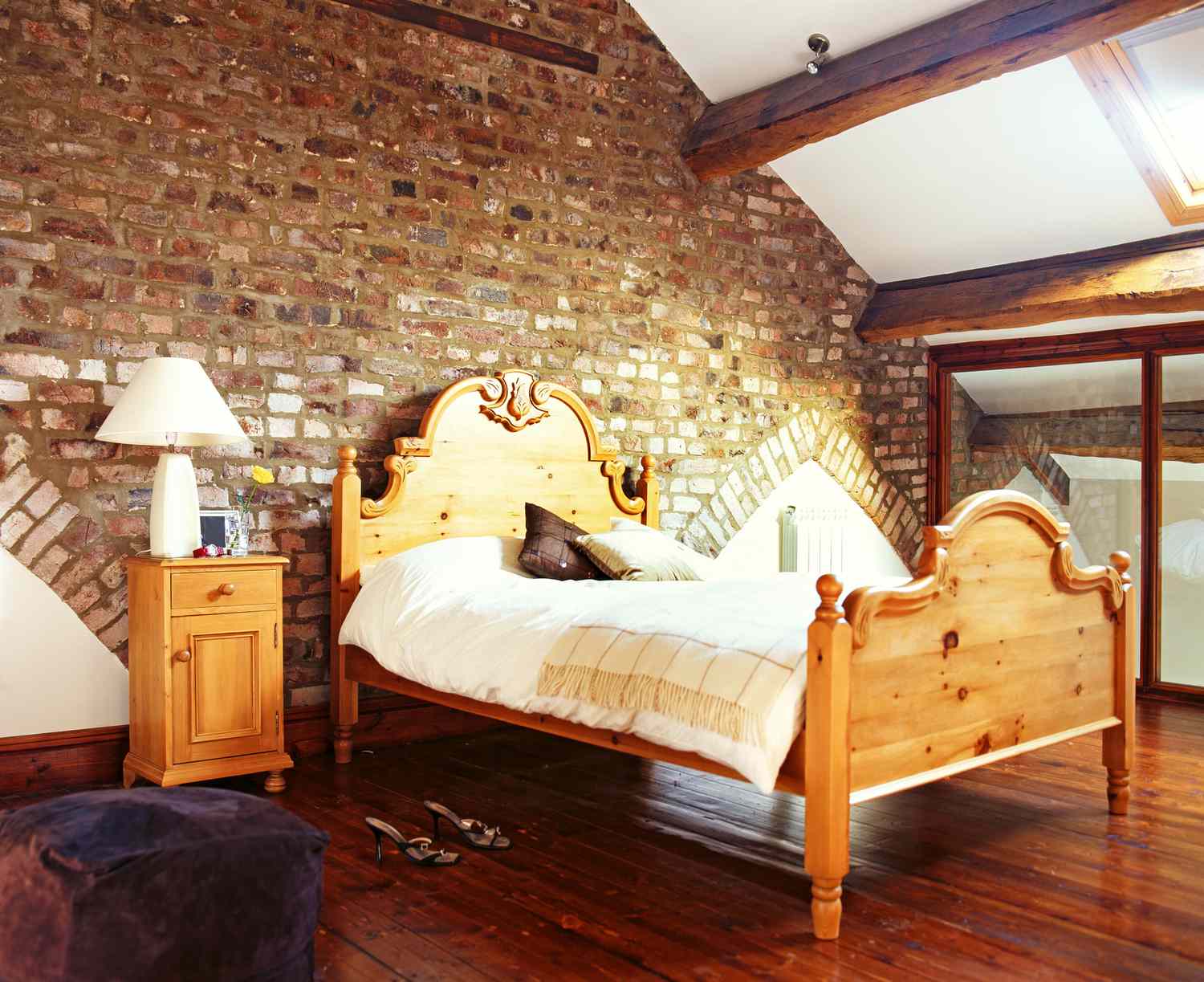 Ein Doppelbett mit einem Holzrahmen steht auf einem Dachboden