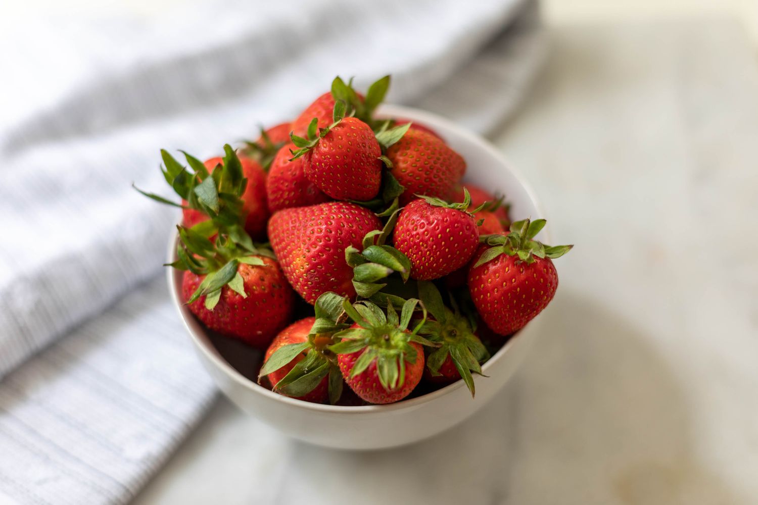 Red strawberries in a small white bowl