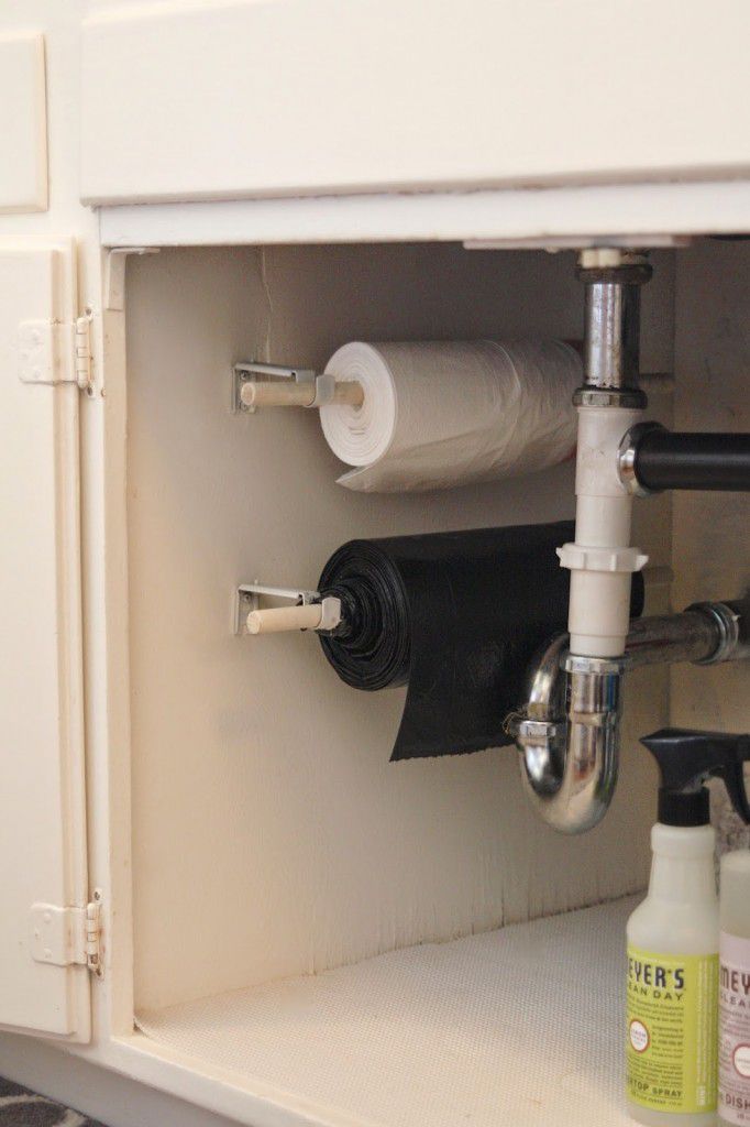 Trash bags hanging on rods in a cabinet.