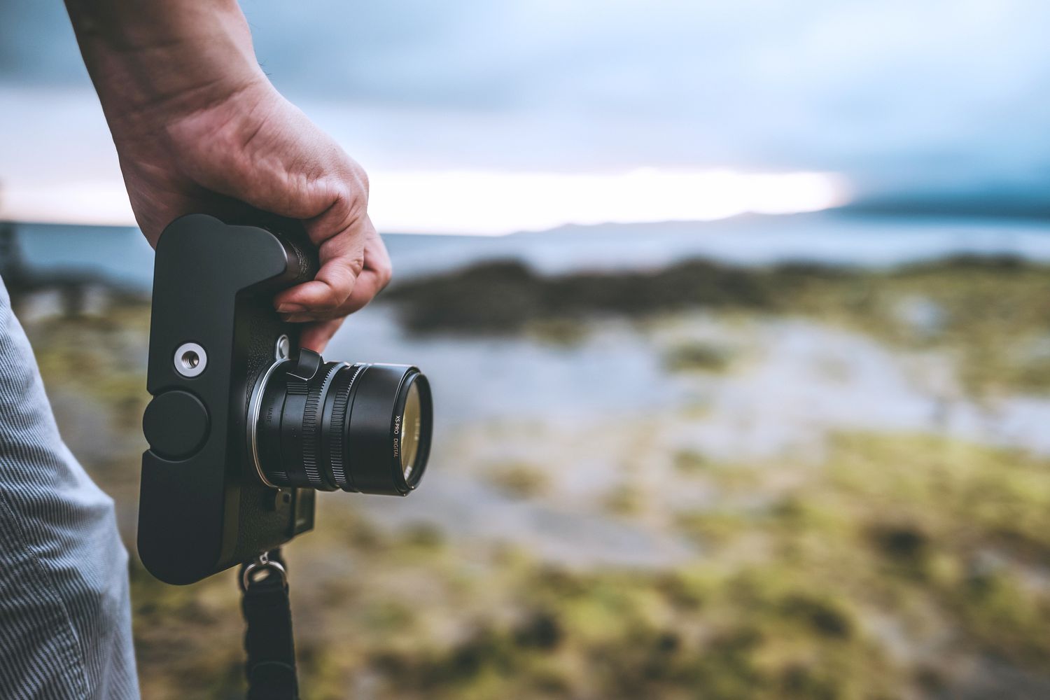 Une personne tenant un appareil photo sur le côté avec un paysage flou en arrière-plan