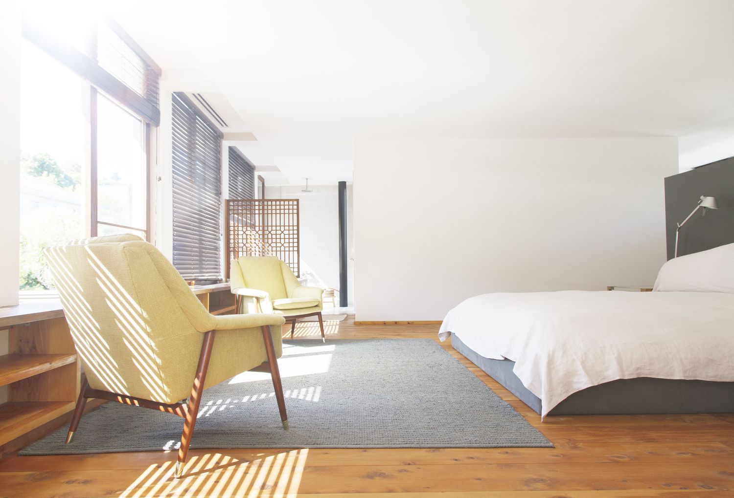 Sillones, alfombra y cama en dormitorio moderno