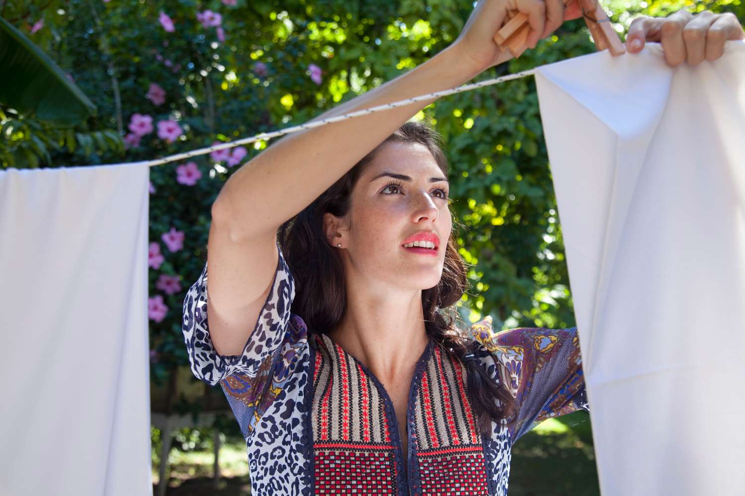 Frau hängt Wäsche an einer Wäscheleine im Freien auf.