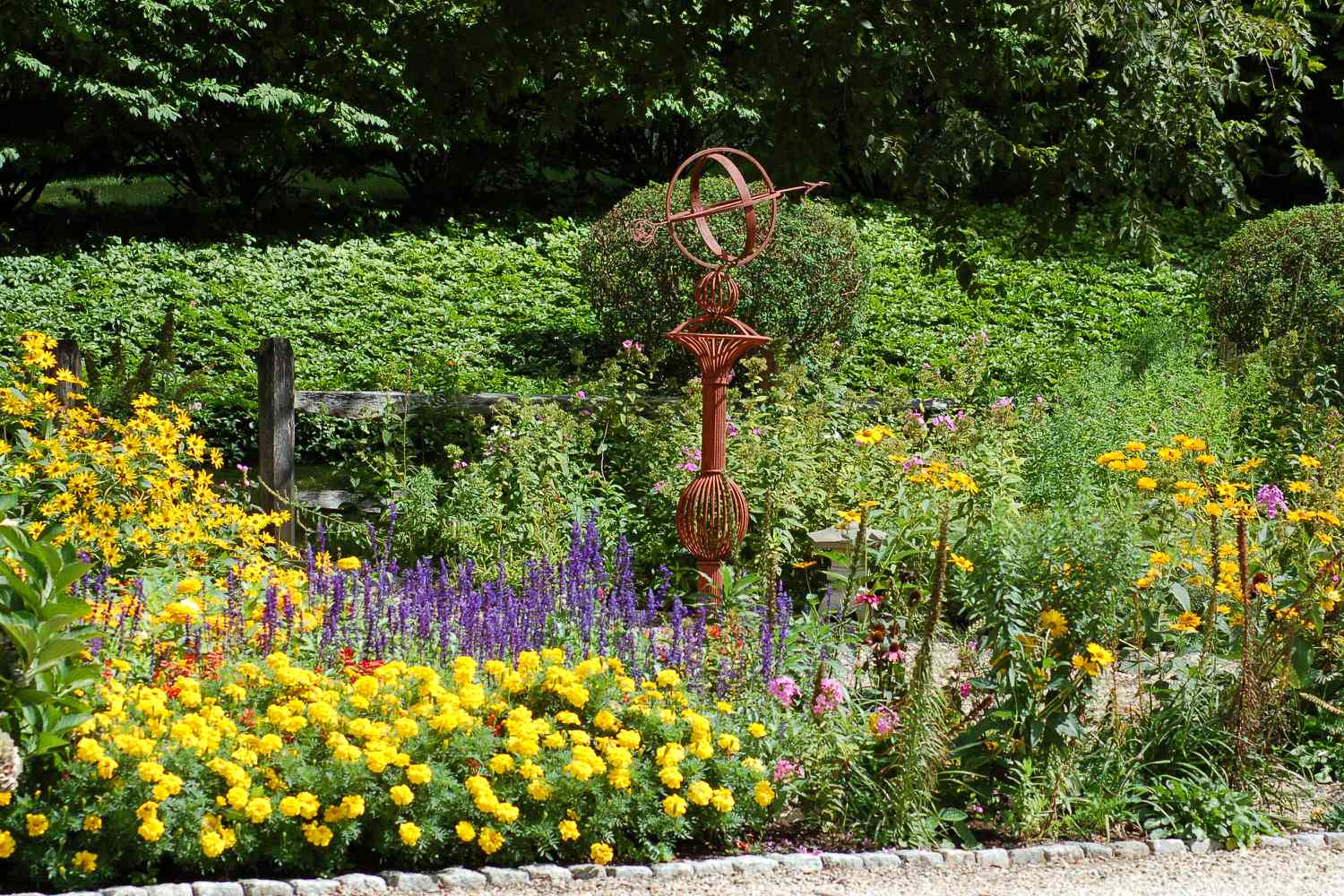 Ein Blumenbeet mit viel Interesse. Es hat sogar Gartenkunst.