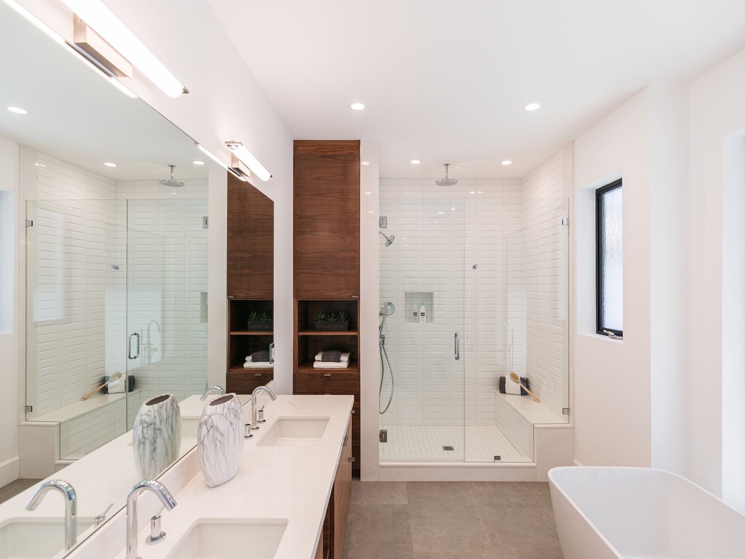 Banheiro moderno com gabinete de madeira cercado por paredes e bancadas brancas
