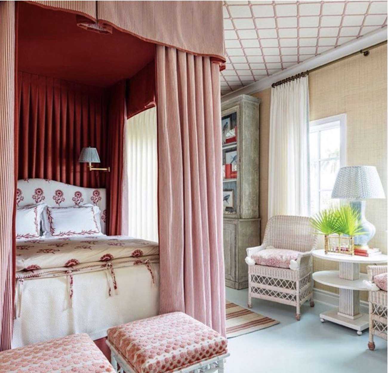 dormitorio con colores rojo y rosa contra paredes crema y muebles de mimbre