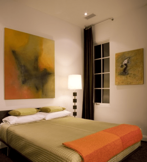 Chambre à coucher marron, vert et orange avec des œuvres d'art sur le mur