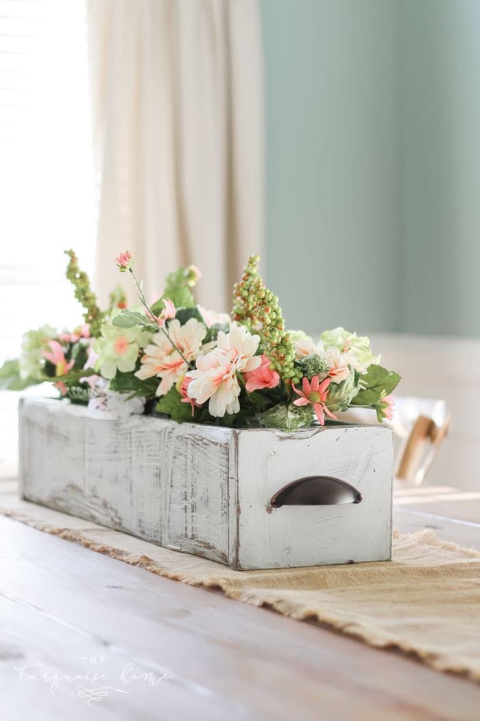 Eine Holzschublade auf einem Tisch mit Blumen darin