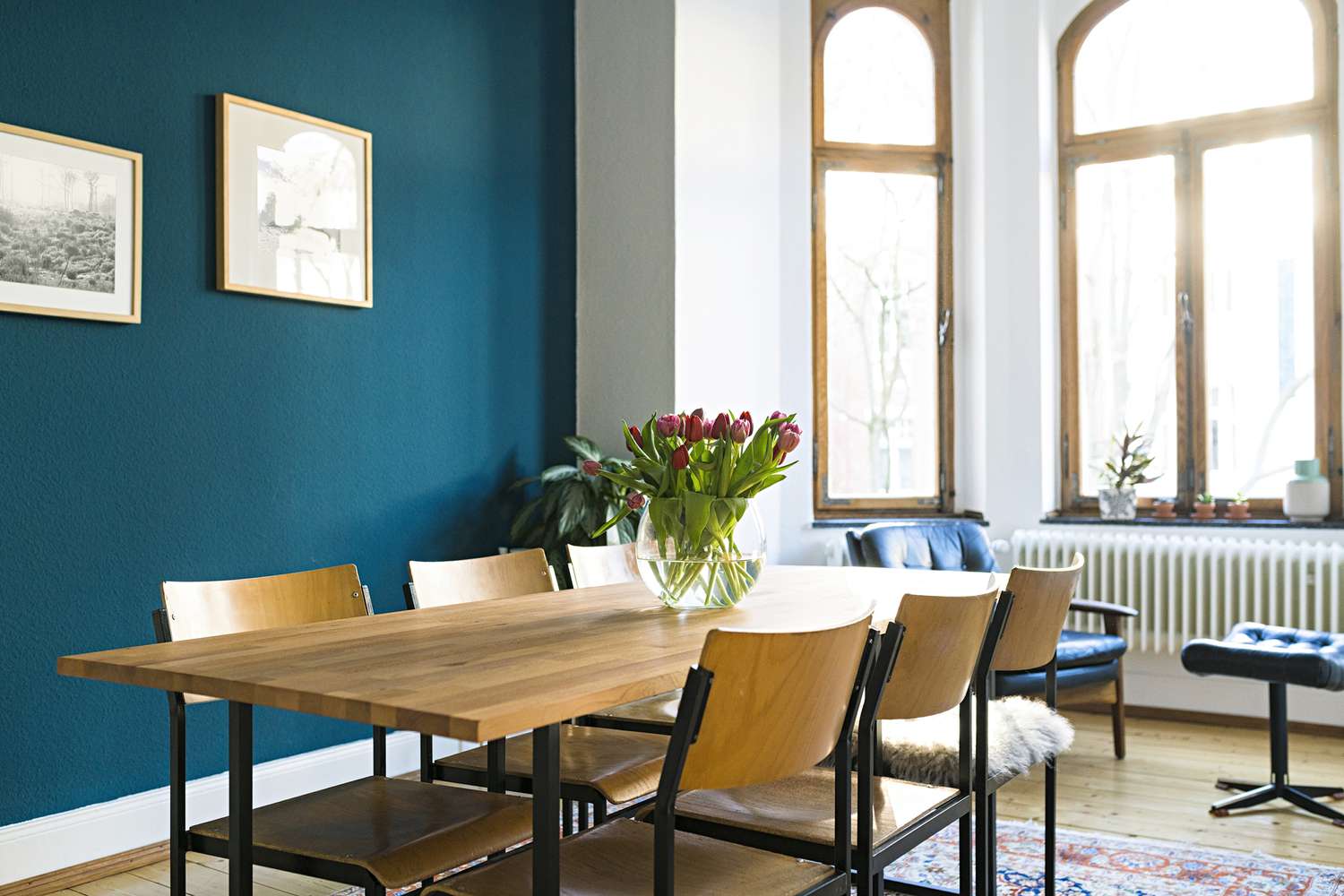 Sala de jantar com parede de acento azul escuro e janela grande.