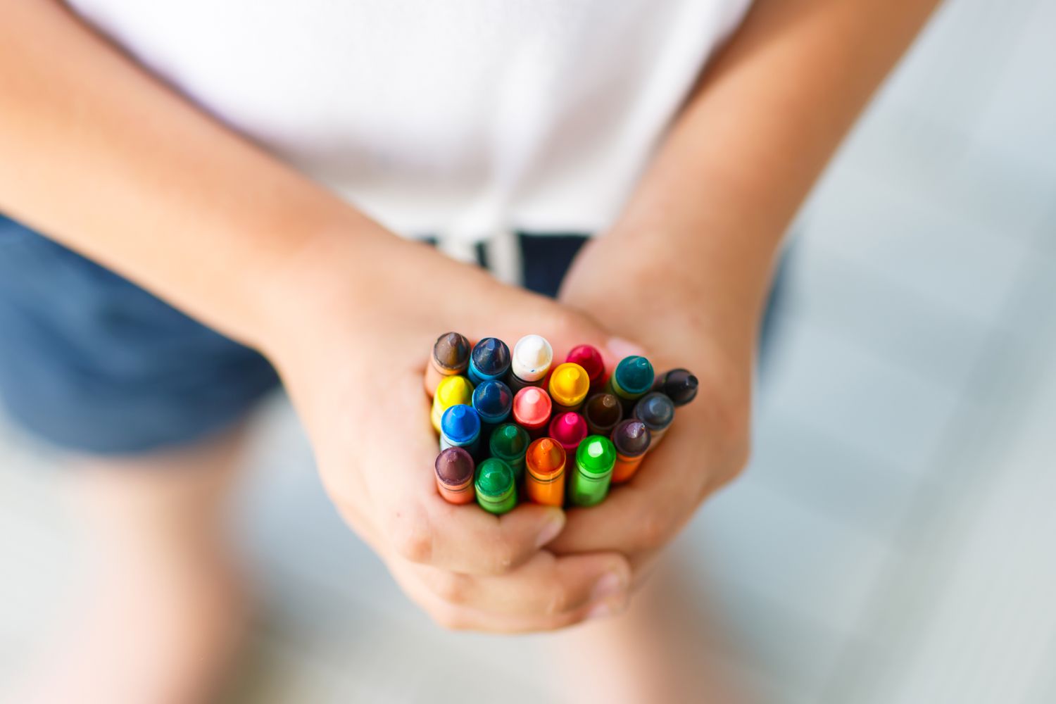 Kinderhände mit vielen bunten Wachsmalstiften