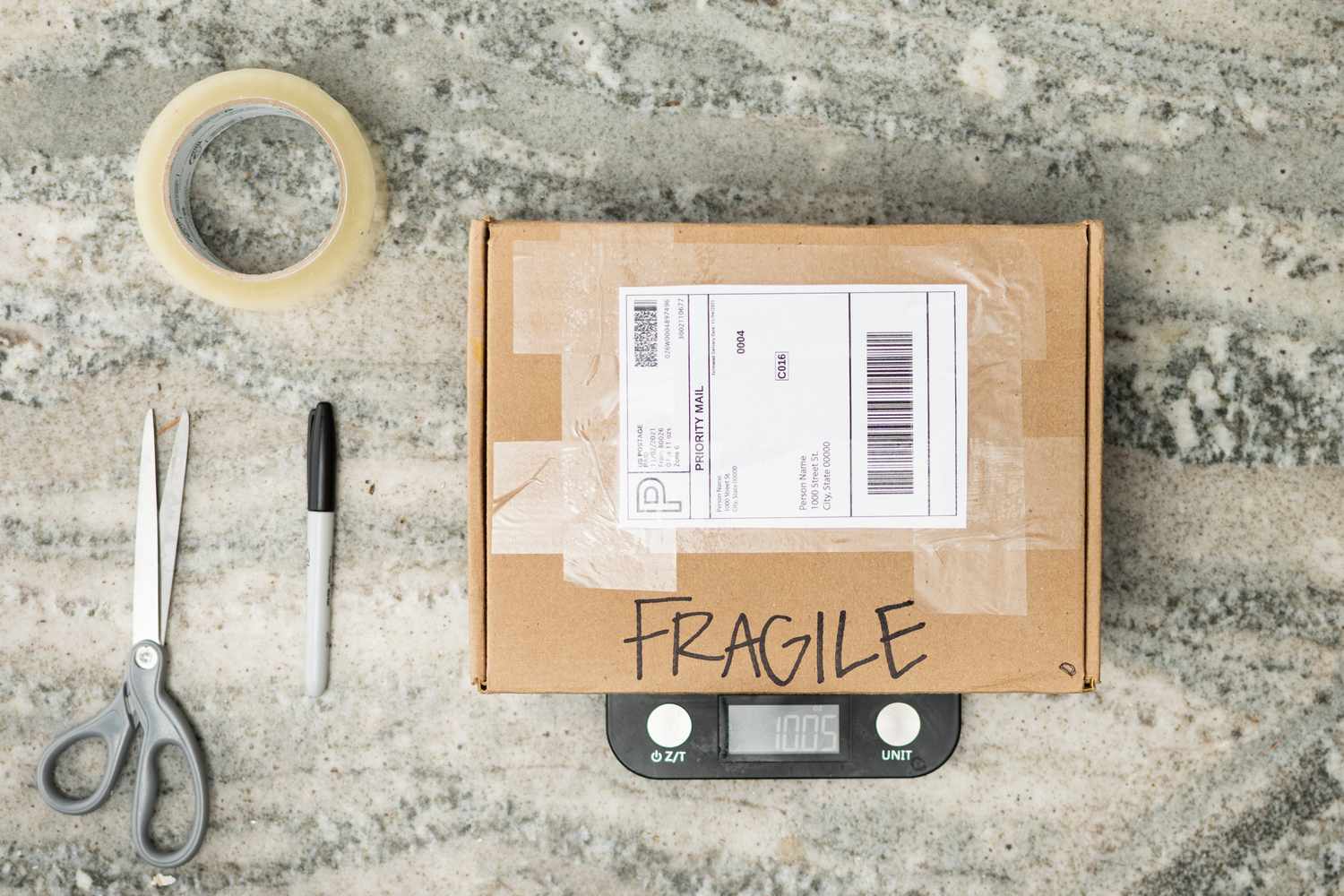 Caja de cartón pegada con cinta adhesiva con etiqueta de envío y pesada en báscula