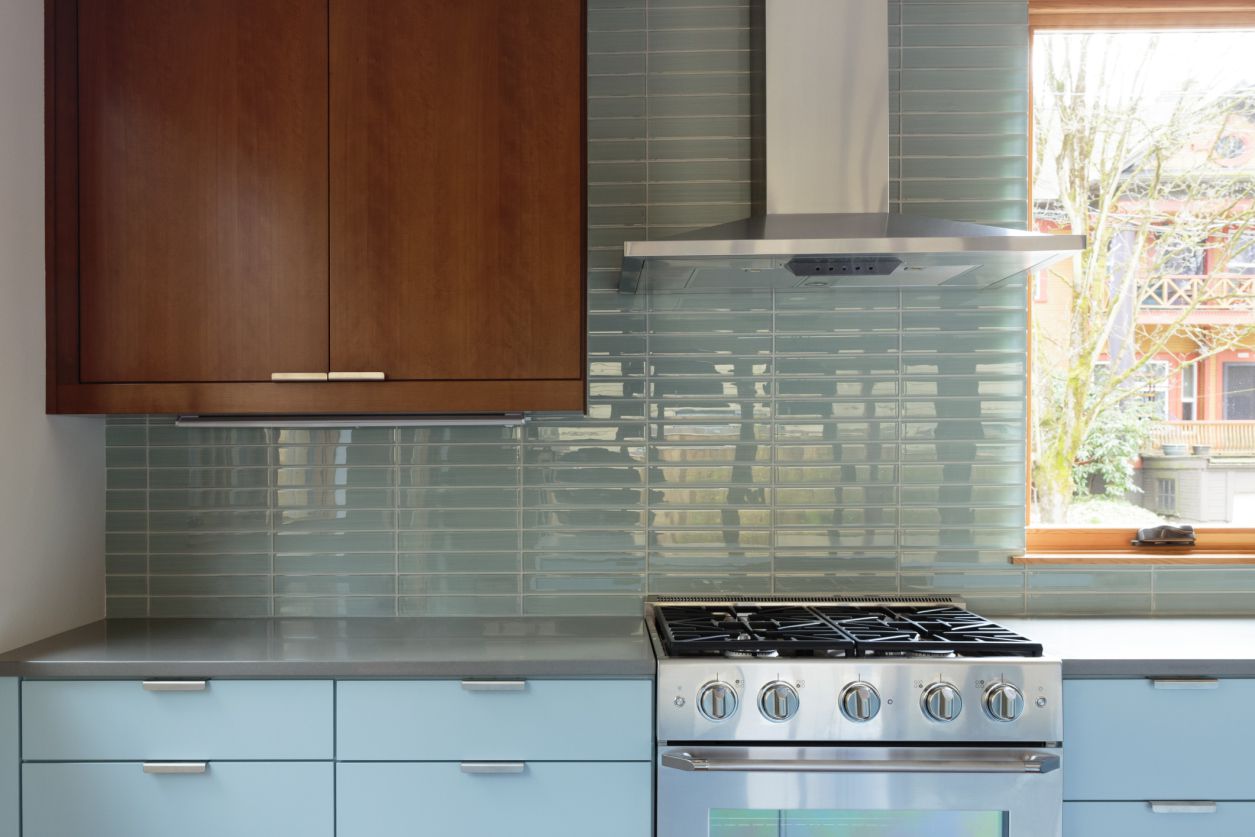 Cozinha com backsplash azul e armários de madeira