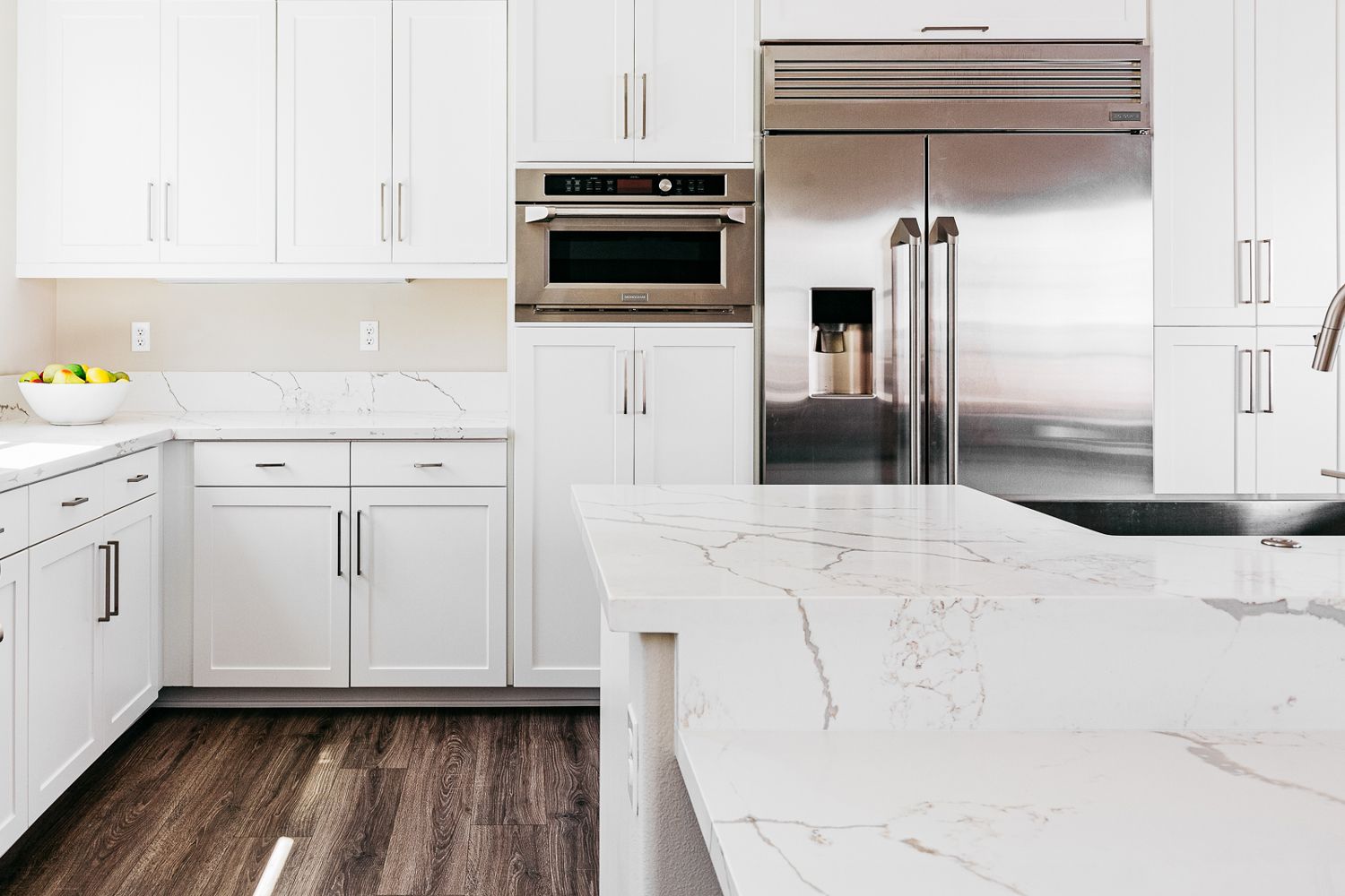 Cozinha minimalista com armários brancos e bancadas de mármore
