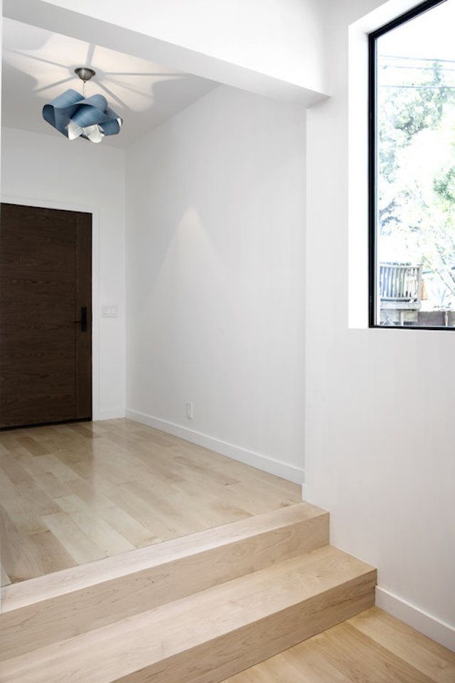 heller moderner Eingangsbereich mit Holzfußboden und blauer Leuchte