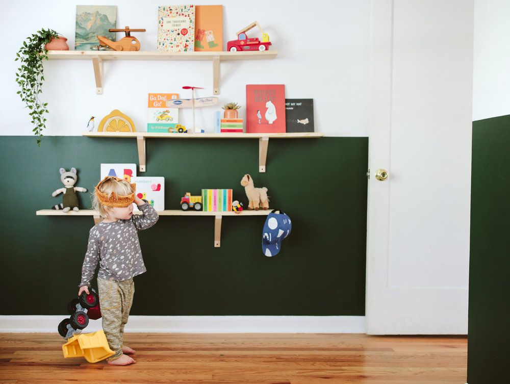 Quarto de bebê com detalhes em verde escuro na meia parede