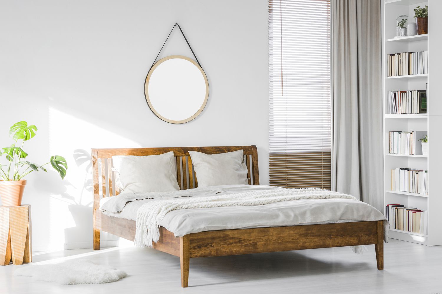 Un marco de cama rústico de madera y una estantería de biblioteca doméstica en el interior de una habitación de hotel natural, iluminada por el sol y con paredes blancas