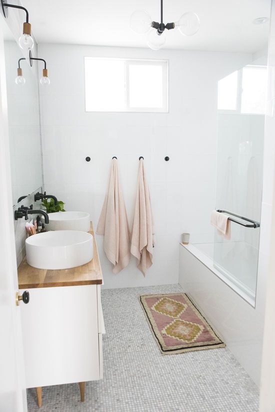 Pink towels hanging next to tub in white bathroom
