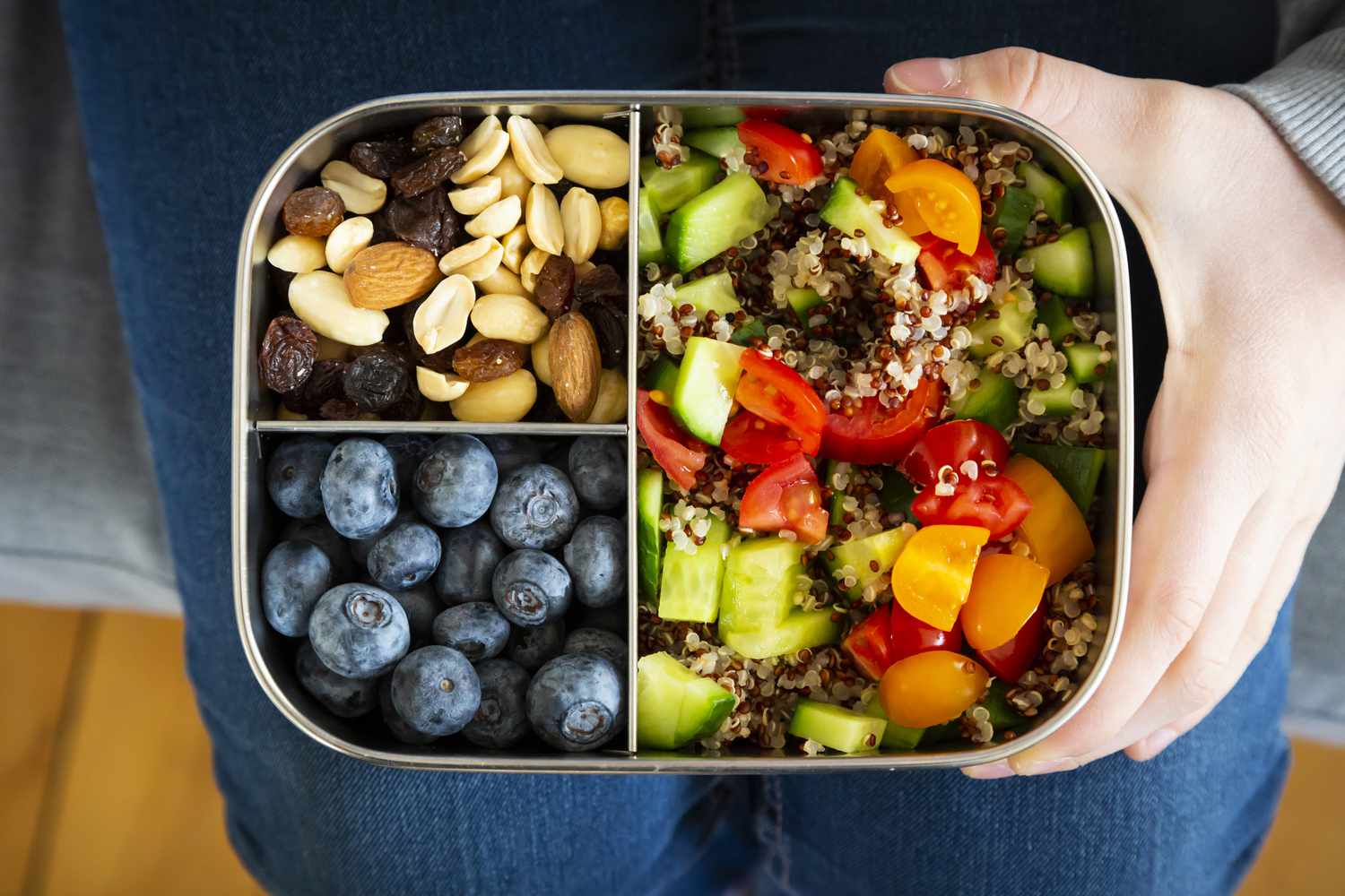 Mädchen hält eine Lunchbox mit Quinoa-Salat, Blaubeeren und Studentenfutter