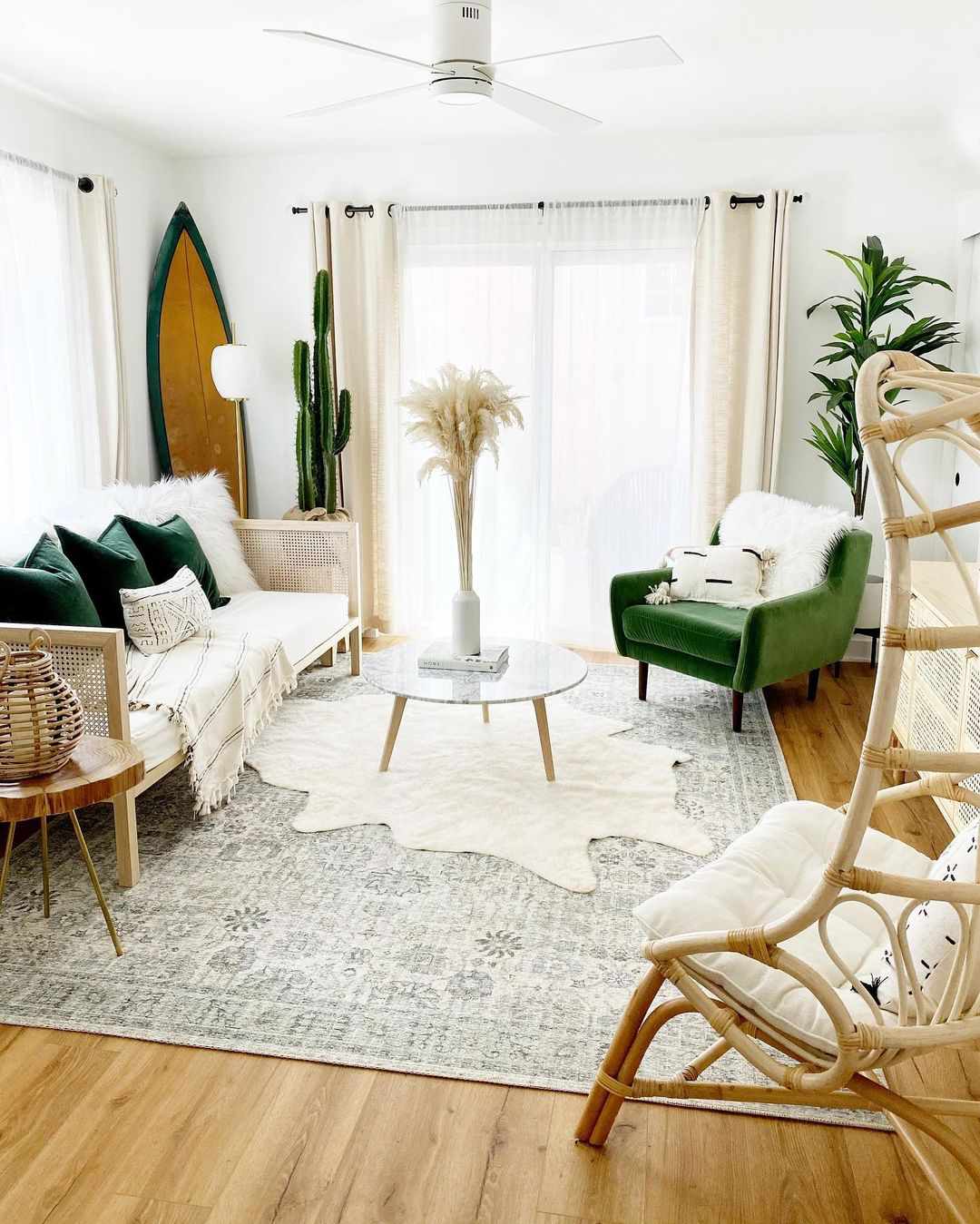 Un salon neutre avec des touches de vert profond, une planche de surf dans le coin et deux tapis superposés
