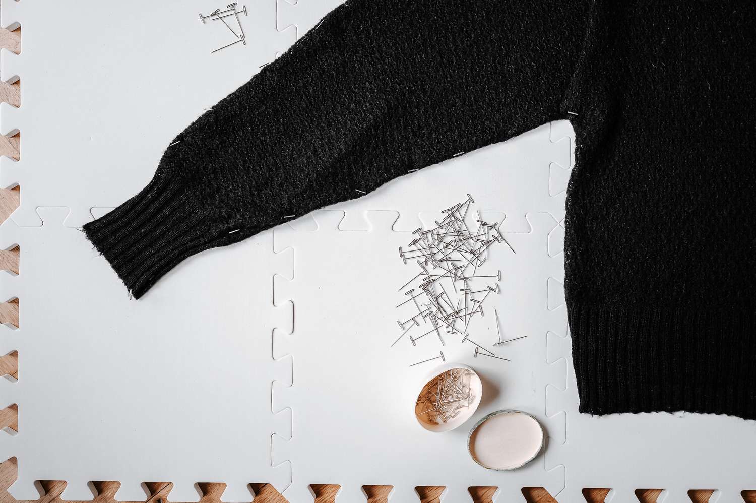 Ein schwarzer Pullover mit Nadeln auf einem Brett
