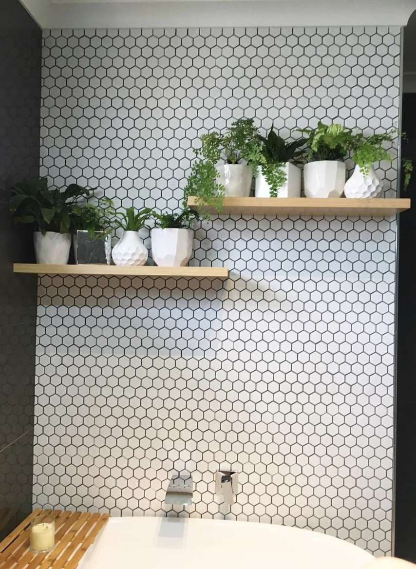 Étagères de salle de bains avec plantes devant un mur de carreaux hexagonaux