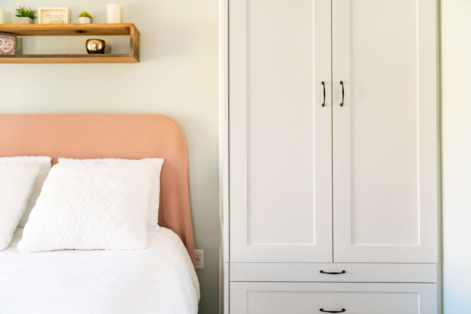 White armoire in between wall and bed