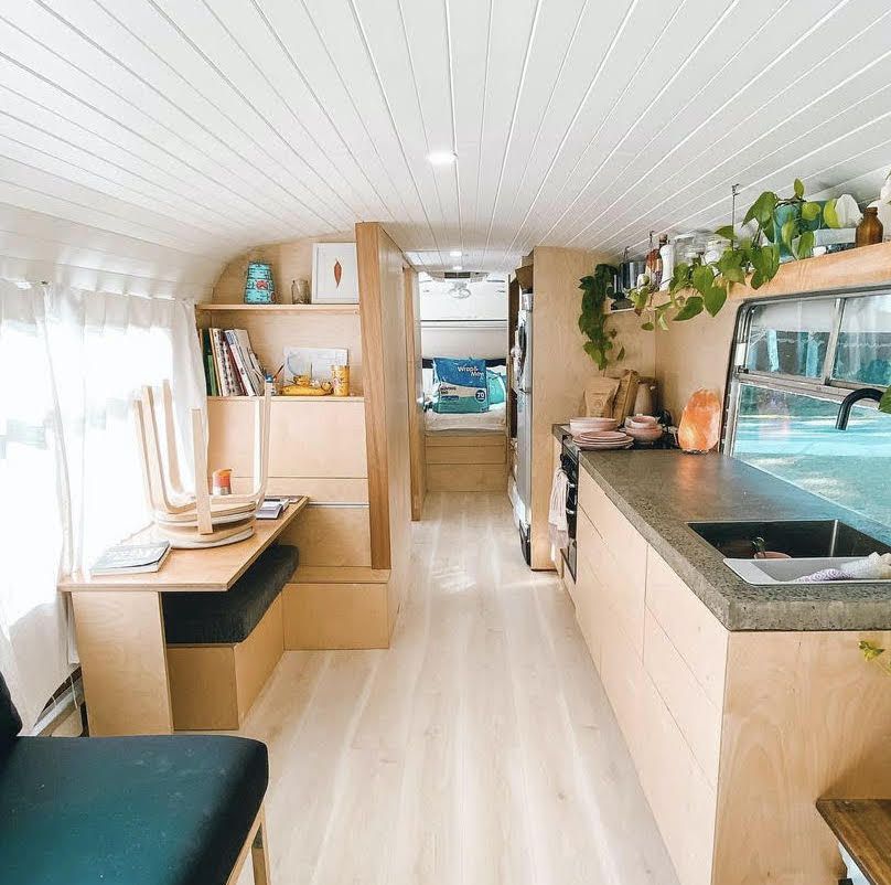 Una cocina reconvertida en autobús escolar de líneas limpias y techo blanco