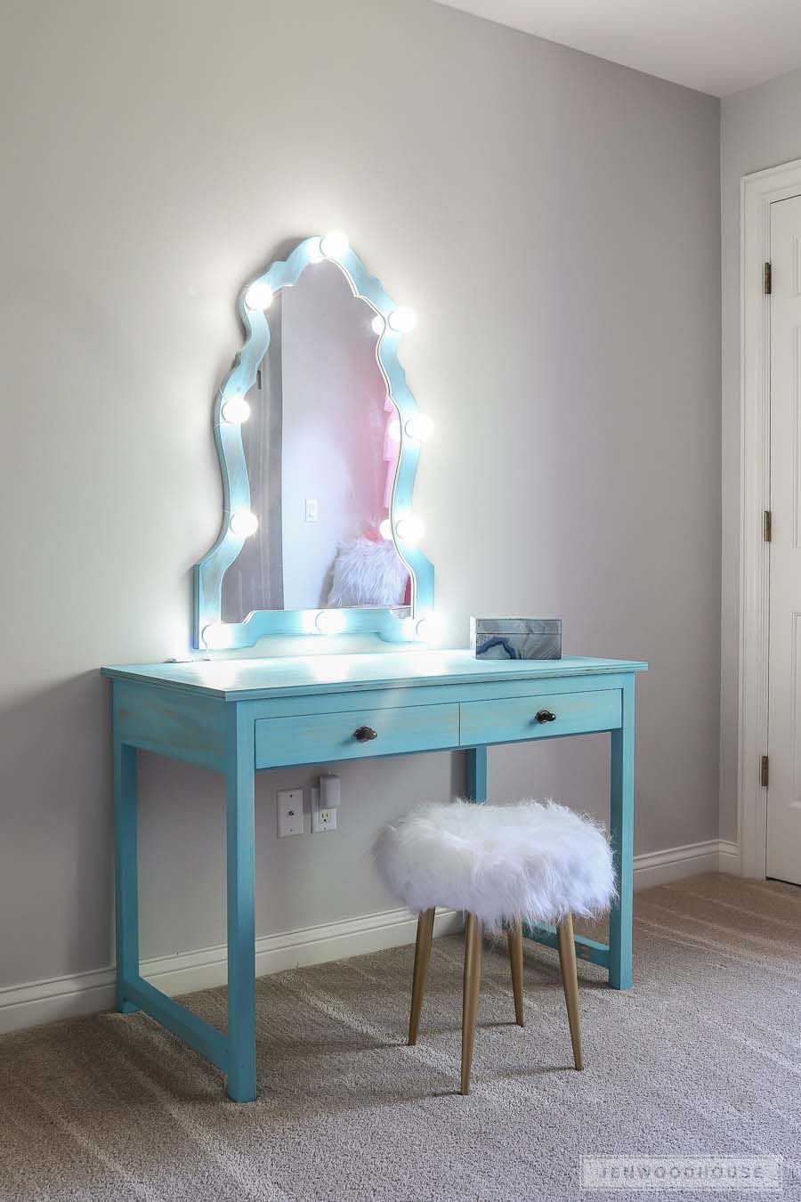 Ein blauer Waschtisch mit einem beleuchteten Spiegel