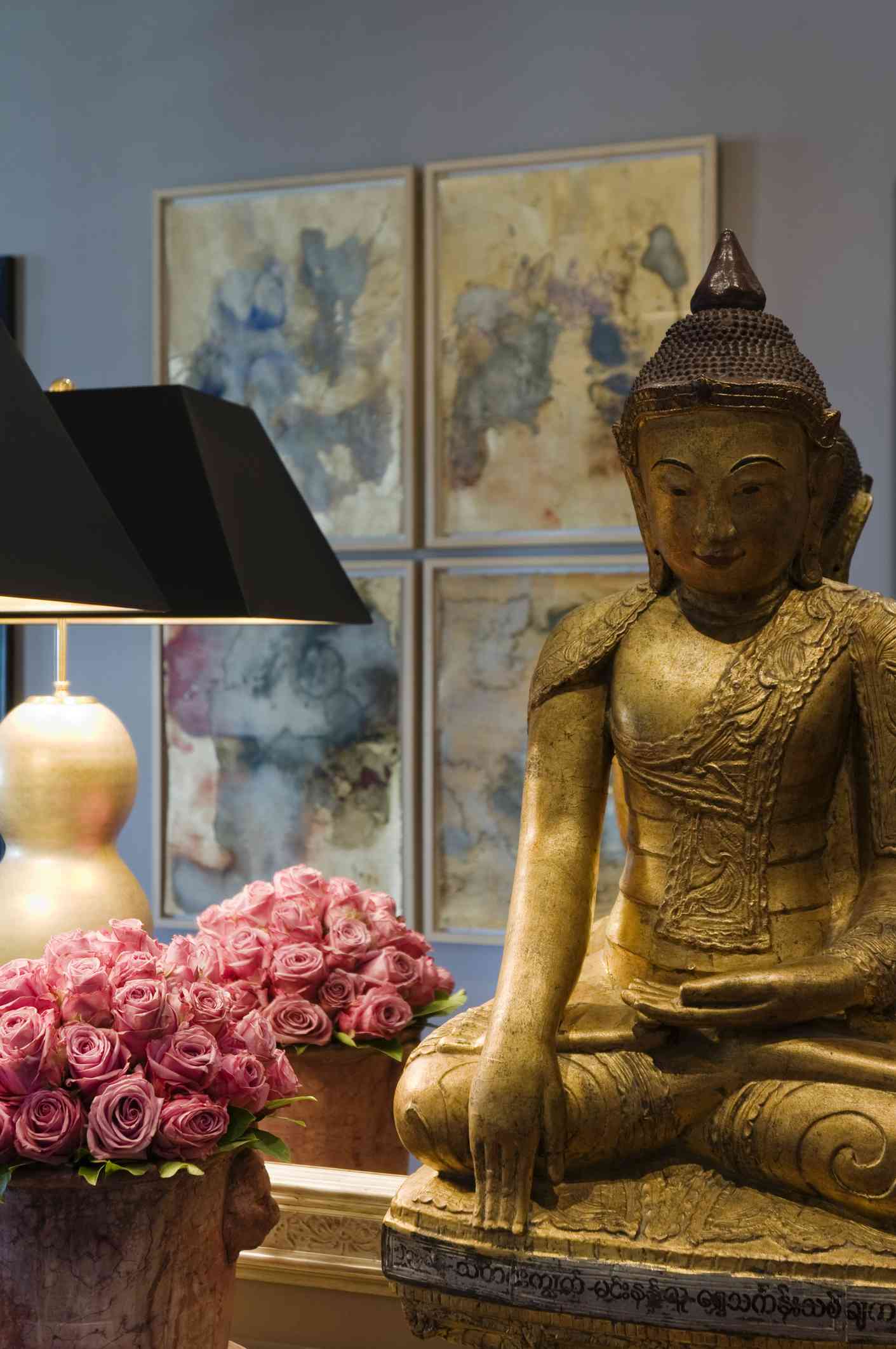 buddha auf einem Tisch mit Spiegel, Blumen und Lampe