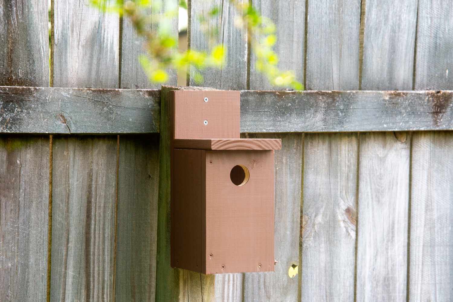 Ein braunes Vogelhaus auf einem Pfosten.