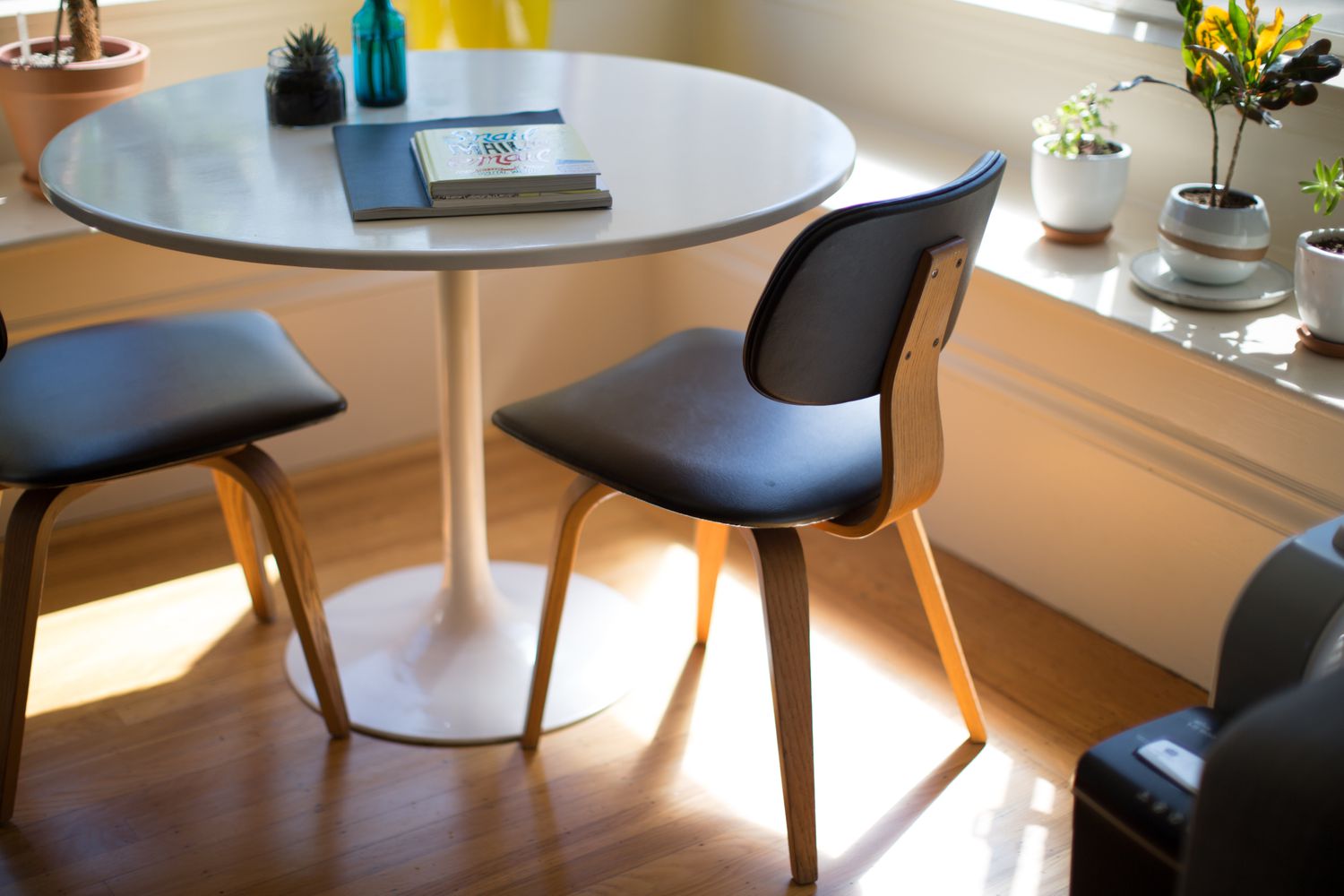 table à manger avec deux chaises et des plantes sur un rebord de fenêtre