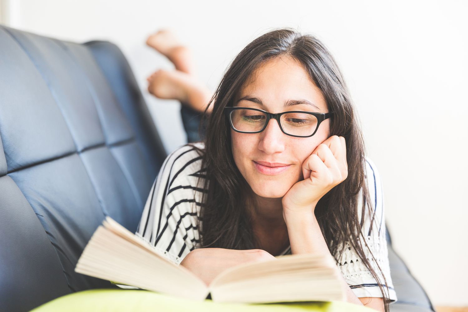 Mujer leyendo en un sofá de cuero