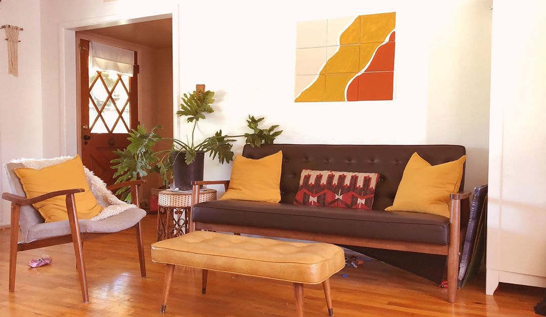 Wohnbereich mit brauner Couch und senfgelben Kissen