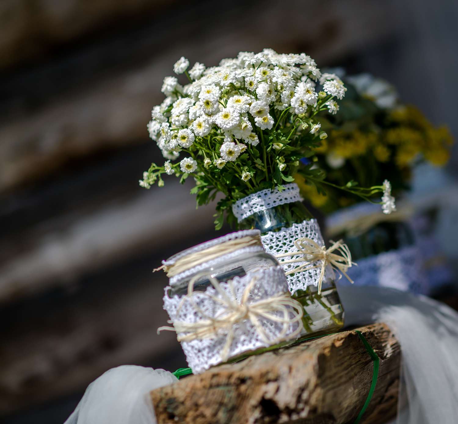 Arranjos de flores em jarras de pedreiro com renda e barbante nas jarras