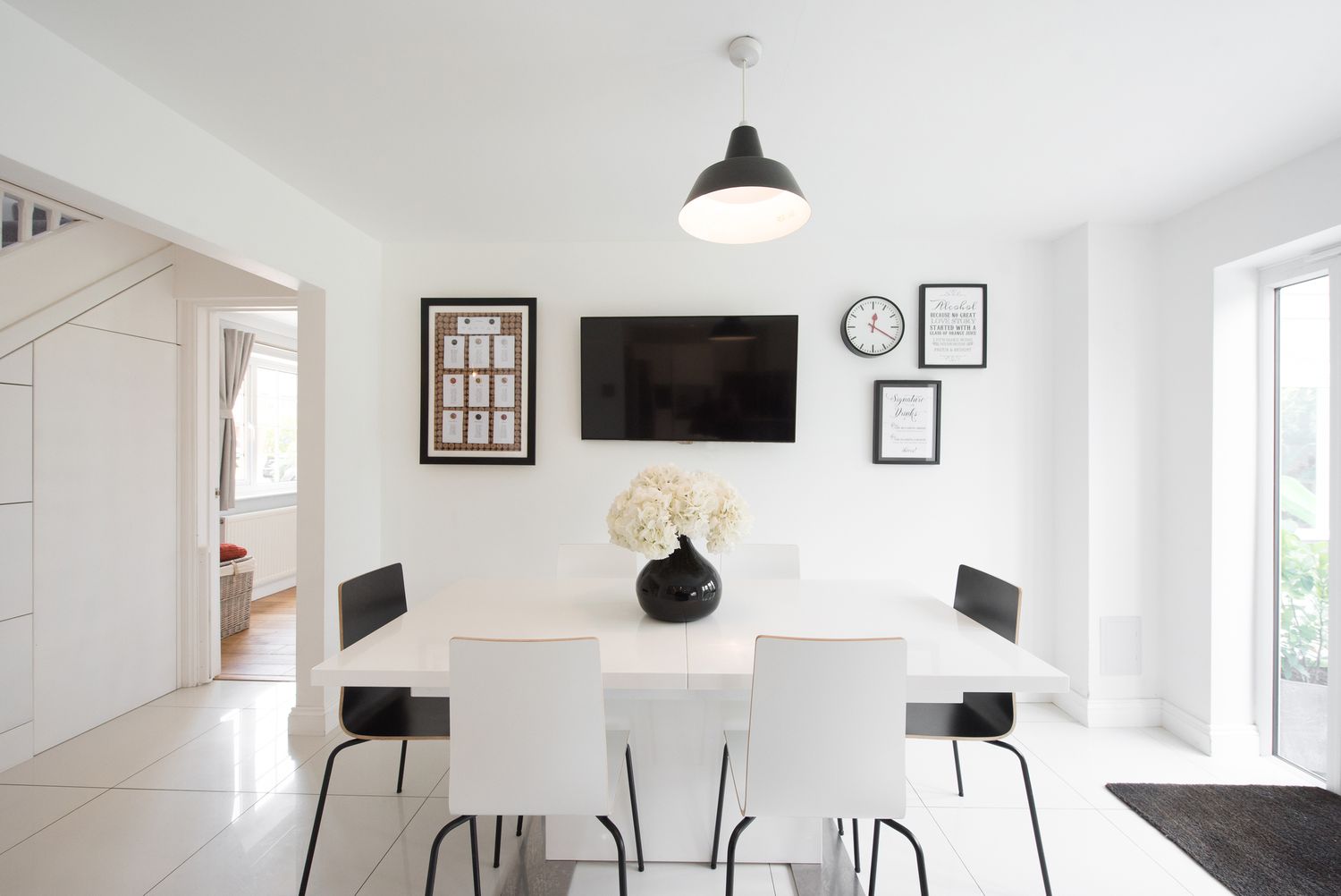 Un comedor blanco minimalista con mesa de comedor blanca y negra