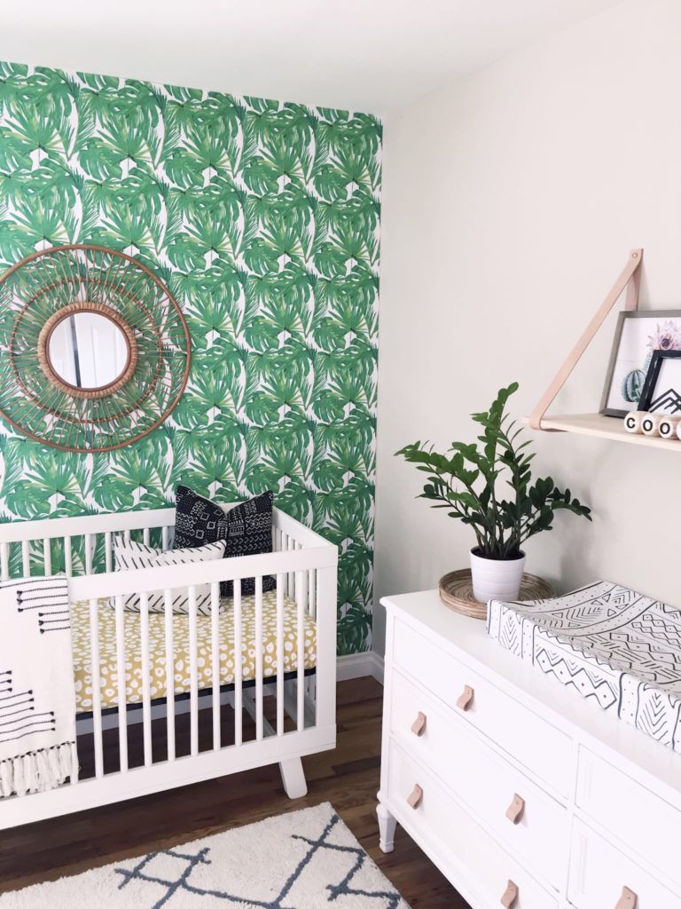 Quarto de bebê com parede verde com estampa tropical e detalhes em amarelo