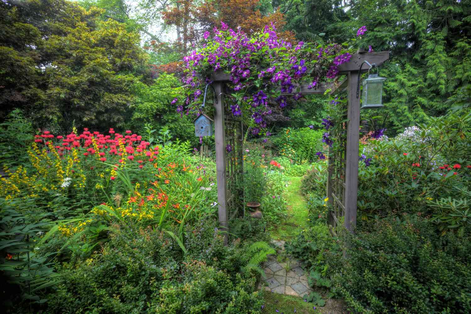 Eine Gartenlaube am Eingang eines Gartenwegs.