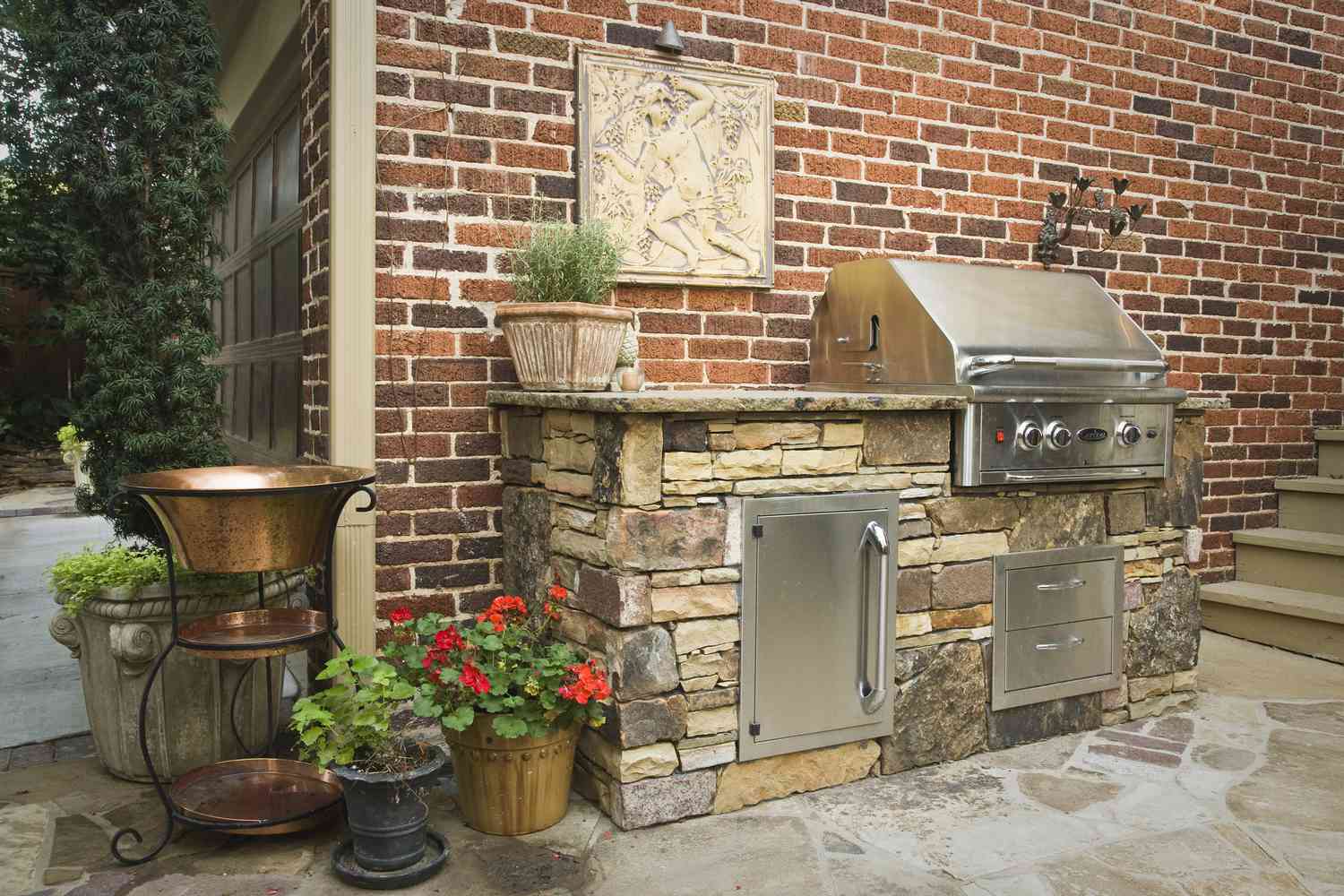 Mueble de cocina de piedra sobre patio de piedra contra pared de ladrillo.