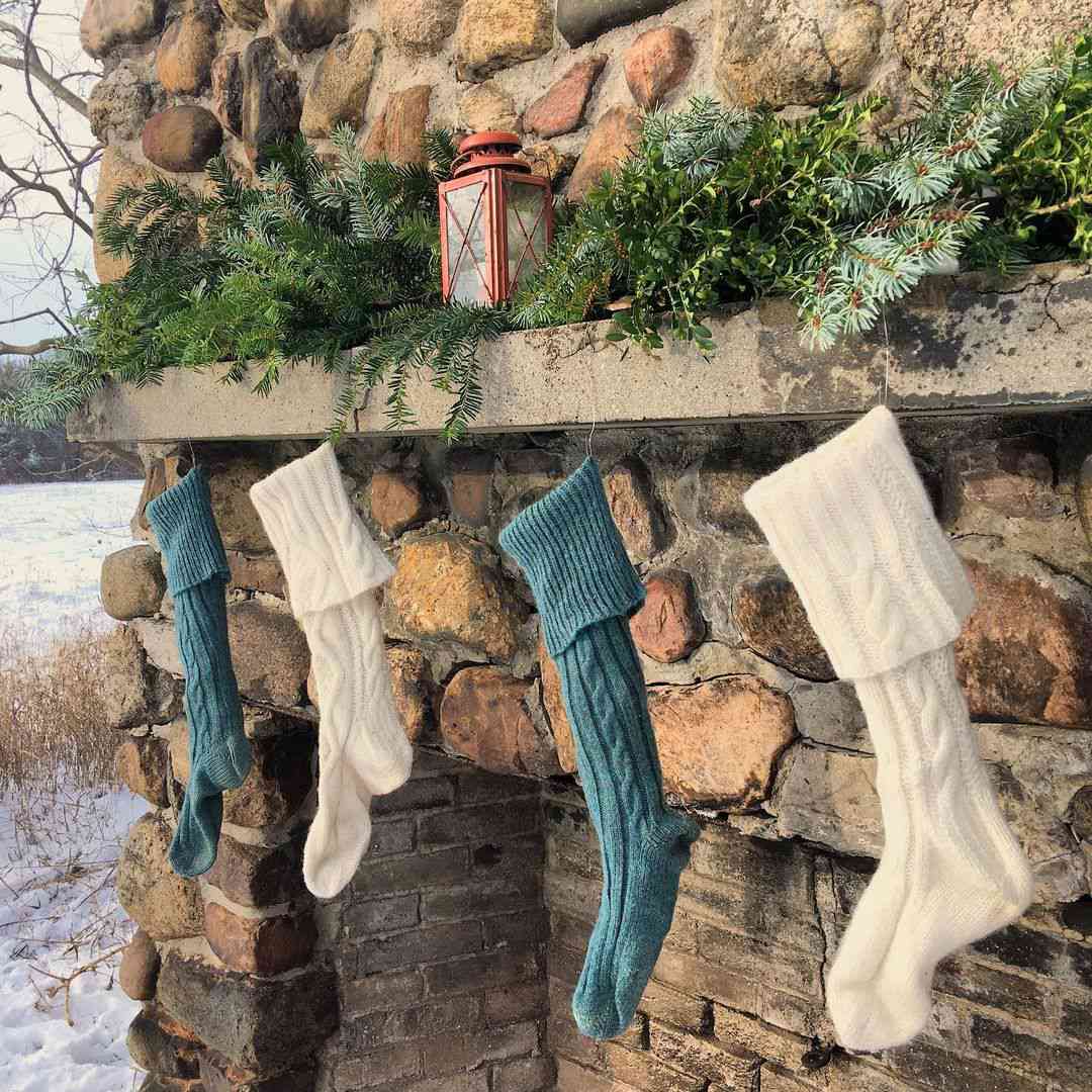 Weihnachtsstrümpfe hängen an einem Steinkamin im Freien.