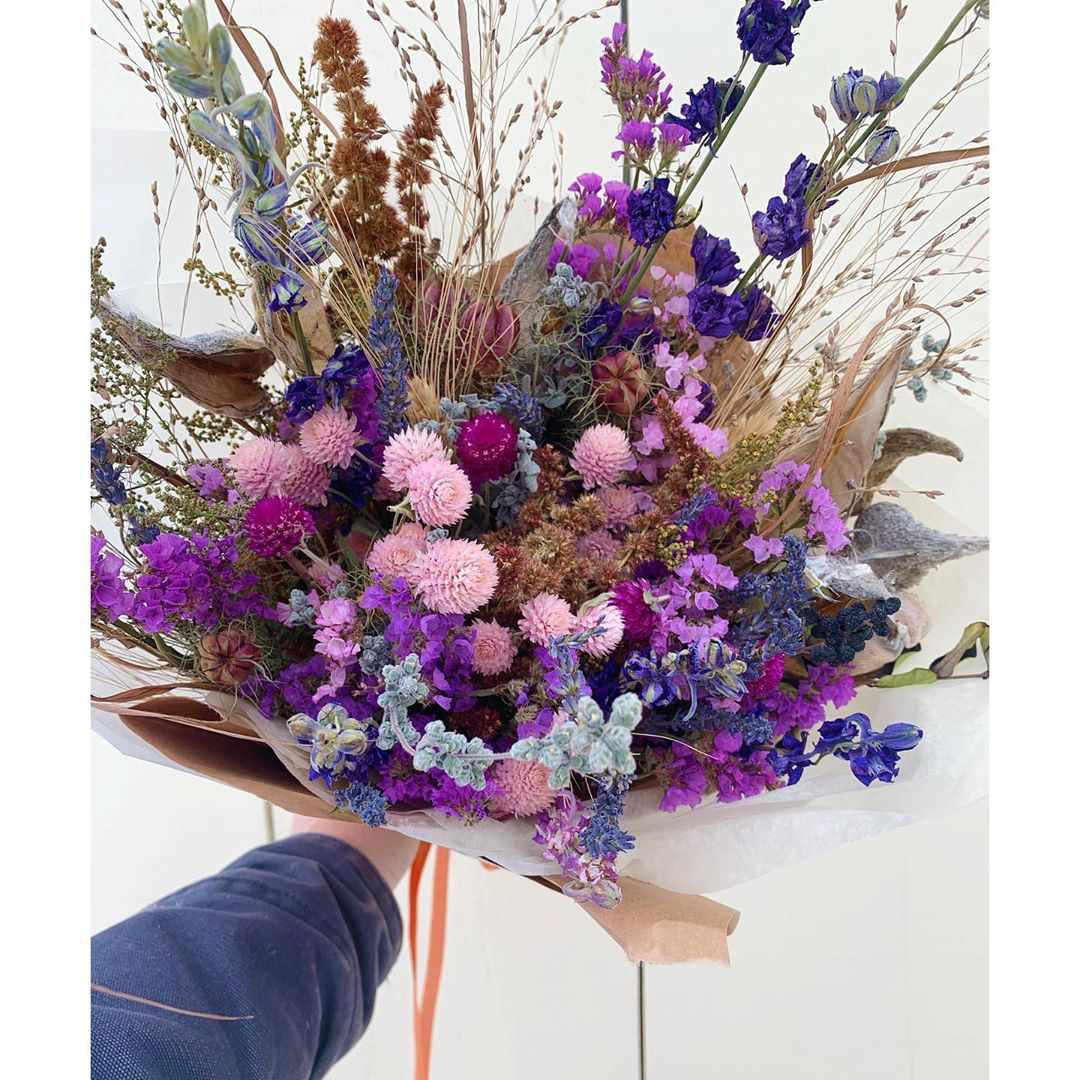 Hand hält Blumenstrauß aus lila und violetten Blüten