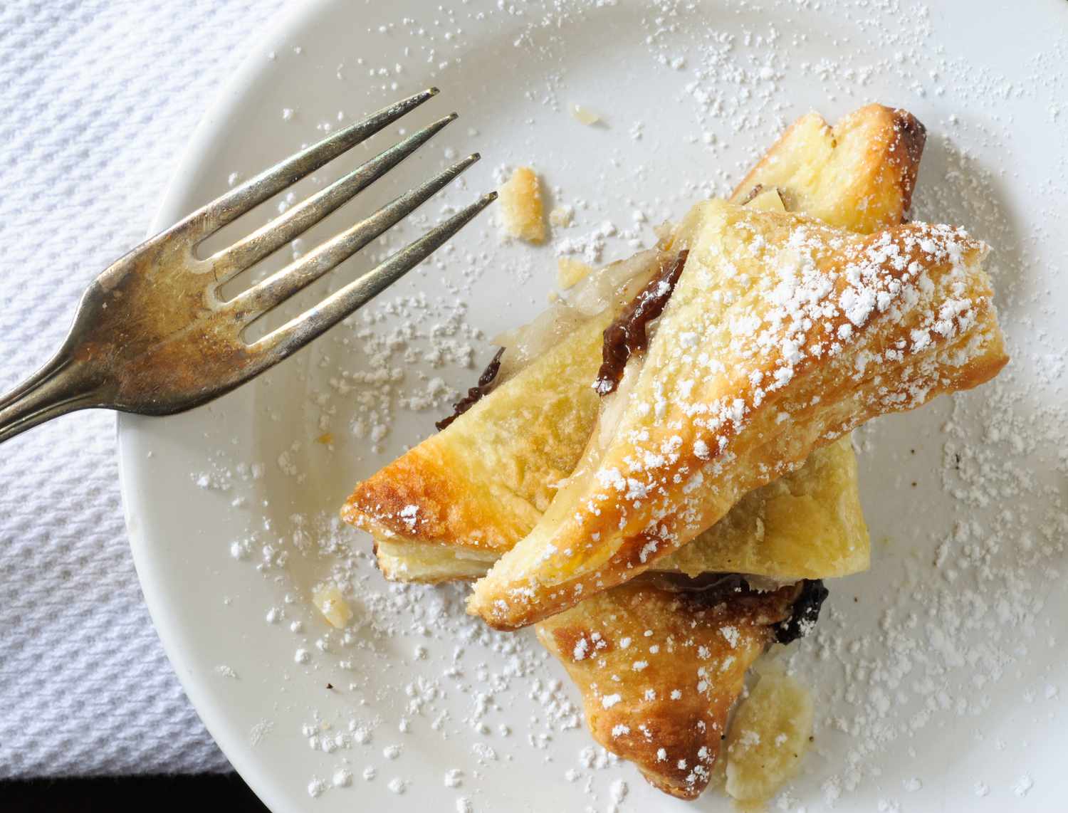 Apple strudel saupoudré de sucre en poudre sur une assiette à dessert avec une fourchette sur le côté