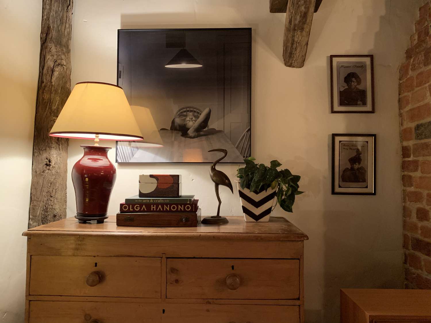 a chest on the set of Master of None features a lamp, books, a statue, art, and exposed wood and beams