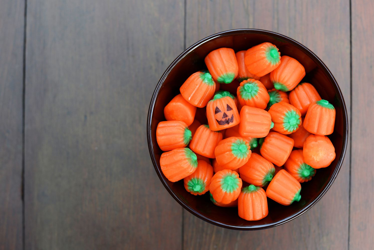Schale mit kürbisförmigen Halloween-Süßigkeiten.