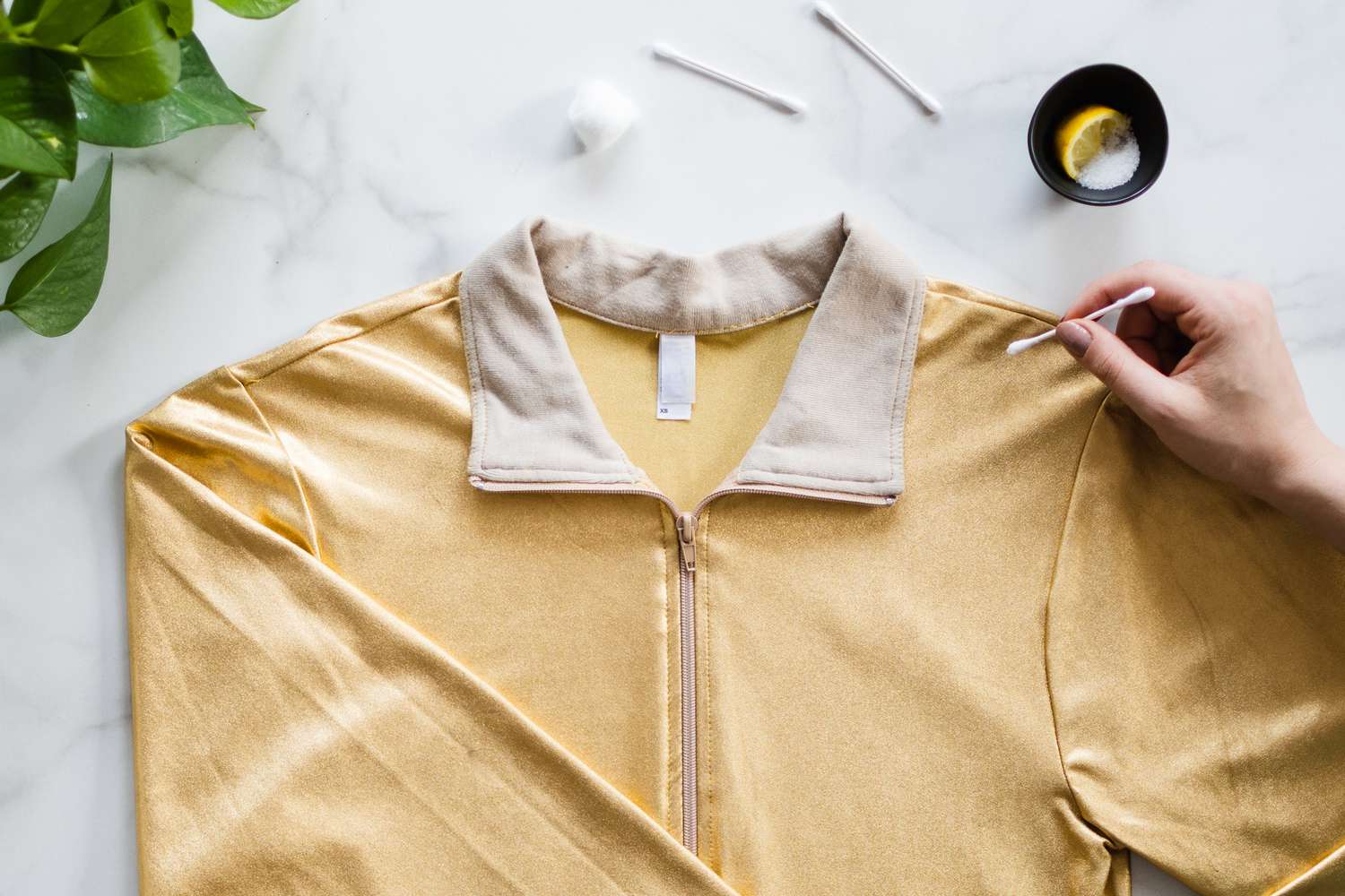 Hisopo de algodón con zumo de limón y sal aplicado sobre la mancha de hilo en la chaqueta metálica amarilla