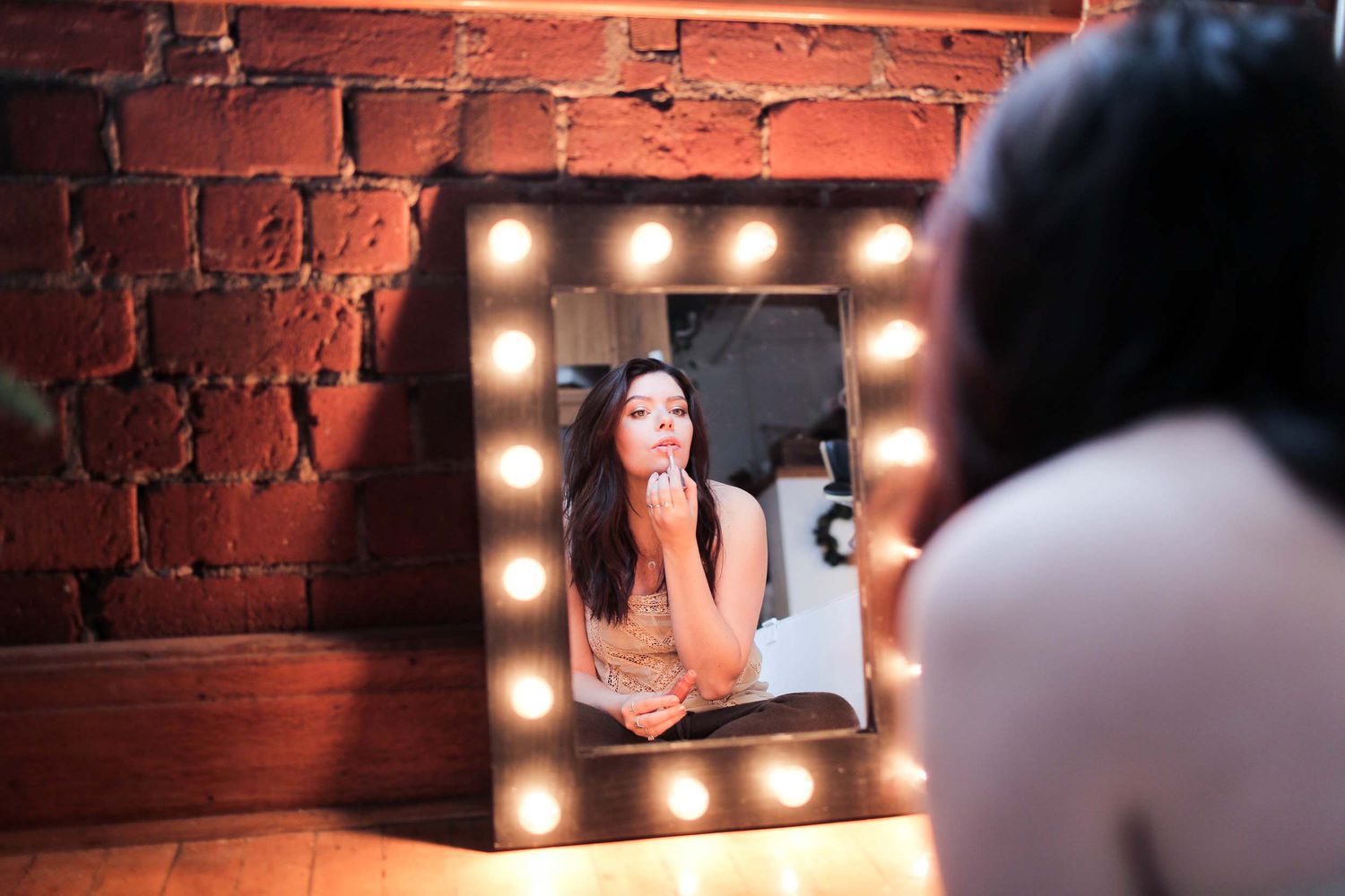 Eine Frau trägt Lippenstift in einem beleuchteten Spiegel auf