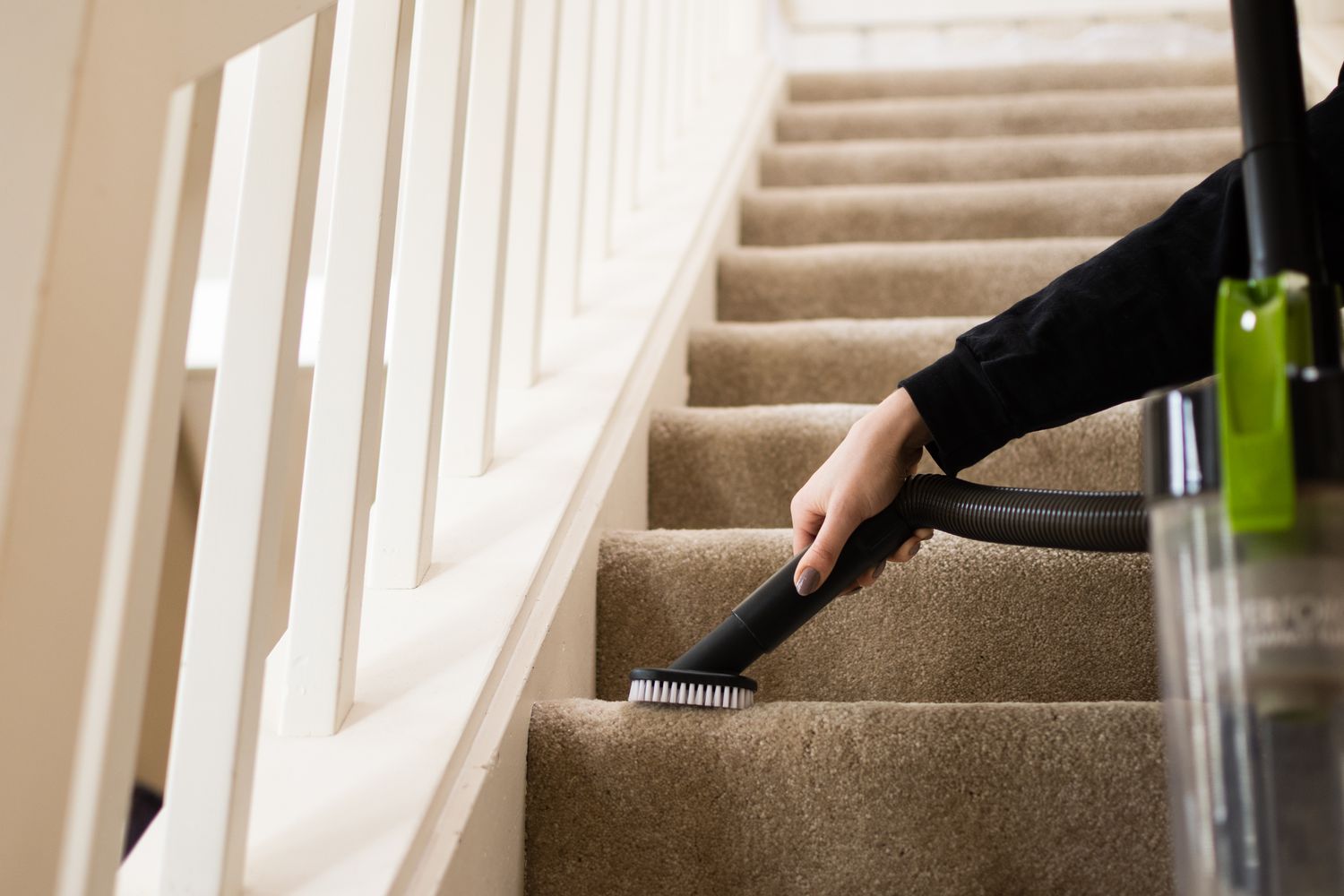 Tuyau d'aspirateur avec accessoire brosse commençant au bas de l'escalier