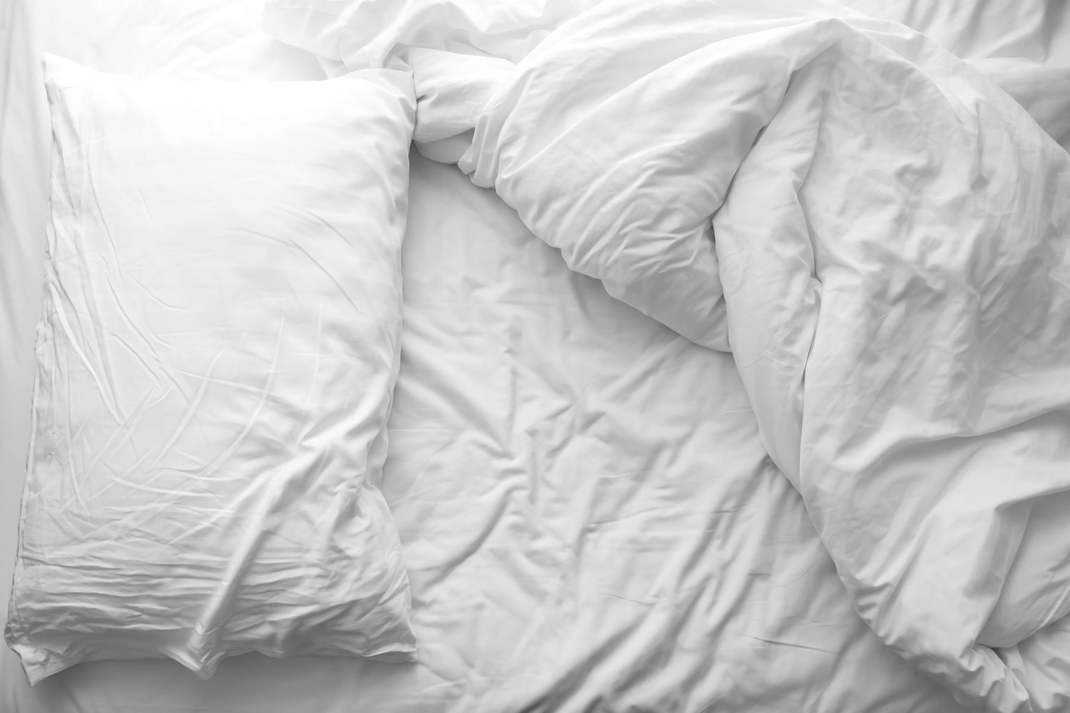 Cama bagunçada. Travesseiro branco com cobertor na cama desarrumada. Conceito de relaxamento após a manhã.