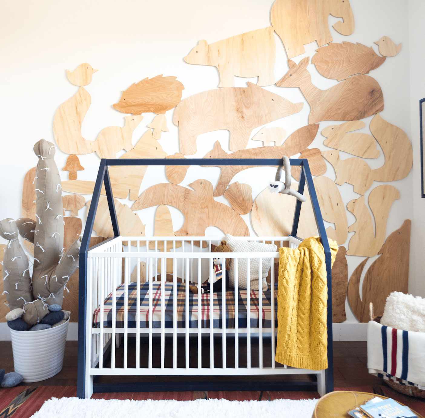 Quarto de bebê de menino com recortes de animais de madeira na parede